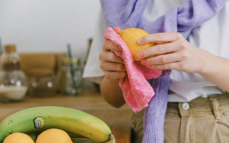 Žena drží v ruce citron a čistí jej hadříkem